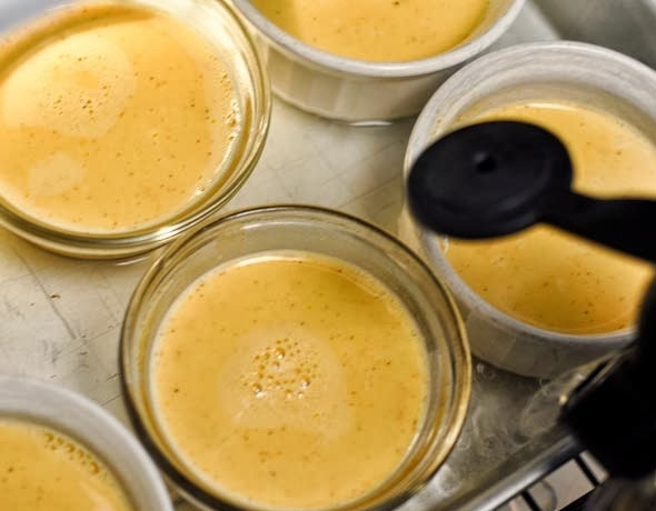 1. Этап. Крем-брюле: Подготовьте порцинные формочки, разлейте в них массу. Возьмите большую форму для выпечки, поставьте в нее все формочки с массой. Налейте в большую форму горячей воды, чтобы она покрывала примерно 2/3 высоты маленьких формочек. Отправьте эту конструкцию в духовку на полчаса.