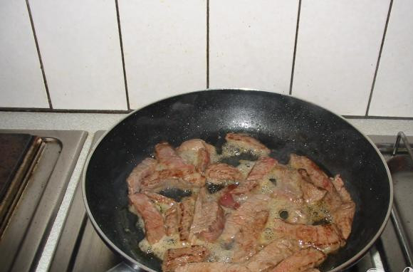 1. Этап. Мясная зажарка: 2. Разогреть 1 ст.л. оливкового масла на максимальном огне. Добавить нарезанную говядину в сковородку и жарить на максимальном огне 3 минуты, пока мясо хорошо не подрумянится. Поворачивать во время обжаривания. Посыпать бульонный кубиком равномерно все мясо и обжарить, часто поворачивая, еще 30 секунд.