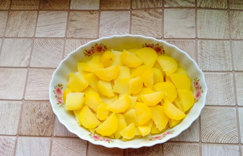 1. Этап. Курица по-французски с картошкой: Картошку очистите, помойте, выложите в кастрюлю с подсоленной водой. Доведите до кипения, проварите 2 минуты и доставайте из кастрюли. Немного охладите, нарежьте кружками и выложите в форму для запекания смазанную маслом.
