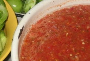 1. Этап. Аджика из зеленых помидоров сырая: Красные помидоры, острый и сладкий перец помойте и прокрутите через мясорубку вместе с очищенным чесноком. Потом добавьте хмели-сунели, соль, растительное масло, все перемешайте.