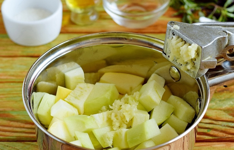 1. Этап. Заготовка из кабачков на зиму Золотая: 2. Складываем в сотейник, добавляем давленый чеснок и перемешаем.