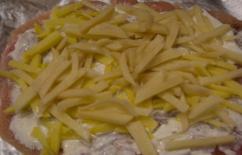 1. Этап. Мясо по-французски из курицы: Смажьте мясо сметаной. Выложите поверх всего нарезанный картофель (равномерно).