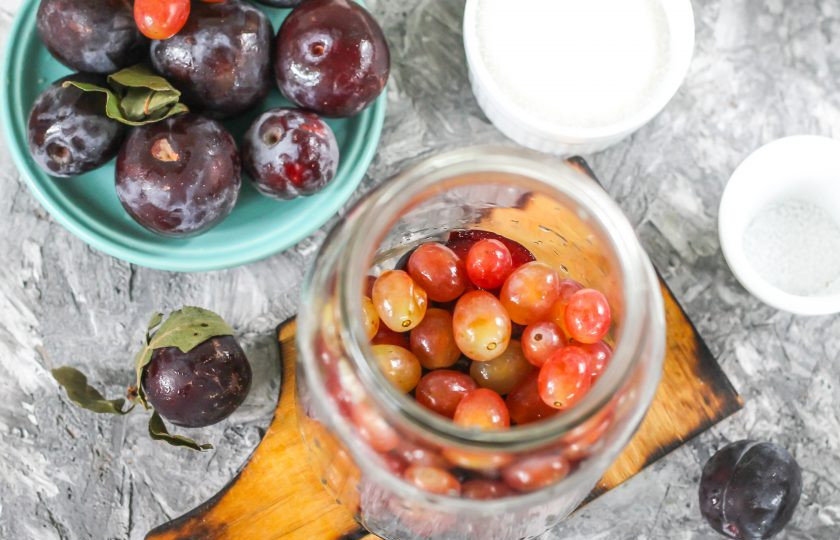 1. Этап. Компот из винограда и слив: Оборвите с кисти виноградные ягоды, промойте их в воде и высыпьте в емкость.