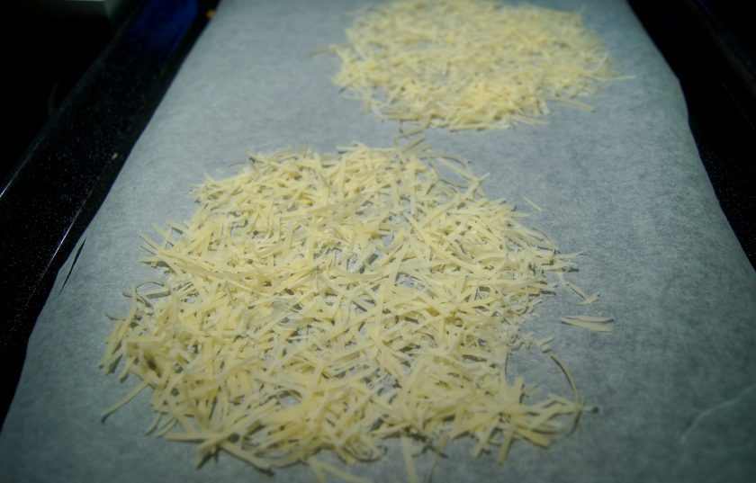 1. Этап. Сырная тарелочка: Возьмите пергамент для запекания, к которому не будет прилипать сыр в процессе приготовления, застелите им противень. Выложите на него тертый сыр, сформировав кружок. Разогрейте духовку до ста шестидесяти градусов, поставьте в нее противень с сыром. Запекайте его минут десять, чтобы он полностью расплавился. Достаньте сыр из духовки и слегка остудите.