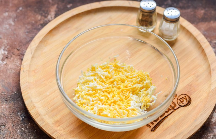 1. Этап. Бутерброды с плавленым сыром и икрой: Куриное яйцо отварите вкрутую — 8-10 минут, после остудите и почистите. Натрите яйцо на мелкой терке и переложите в миску.