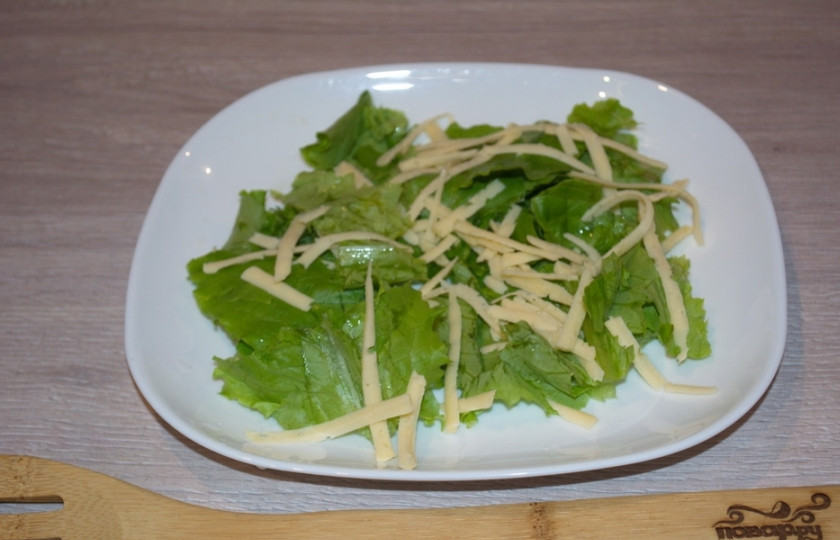 1. Этап. Салат А-ля Цезарь: Натрите на терке твердый сыр. В классическом Цезаре используется пармезан, но можно вполне взять любой доступный сыр твердых сортов. Часть сыра выложите на салатные листья, а часть отложите.