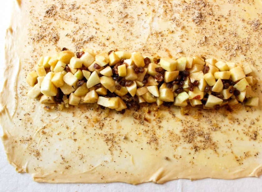 1. Этап. Штрудель классический: 2. Теперь на сковороде растопим сливочное масло и обжарим на нем измельченные орешки. Туда же отправьте яблоки, нарезанные мелкими кубиками. На маленьком огне тушим начинку до мягкости фруктов. Дальше добавим изюм, корицу, сахар и лимонный сок, перемешаем, снимем с огня и выкладываем эту начинку на тесто.