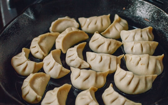 1. Этап. Жаренные китайские пельмени: Отправьте пельмени на сковороду с растительным маслом и обжарьте, пока низ не станет золотистым. Влейте воду, чтобы она покрывала пельмени на половину и готовьте, пока вода не выпарится.