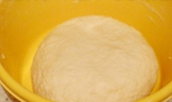 1. Этап. Сардельки в тесте жареные: Хорошо замесите тесто. Почти в самом конце влейте 1 ст. ложку растительного масла, продолжайте мешать. Тесто должно перестать липнуть к рукам. Потом накройте его плёнкой. Уберите в тёплое место примерно на 3 часа, чтобы оно поднялось.