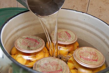 1. Stage. Apricot compote: Place jars with compote in a deep pan with a covered bottom, pour boiling water and sterilize the compote for 10 minutes after boiling again.