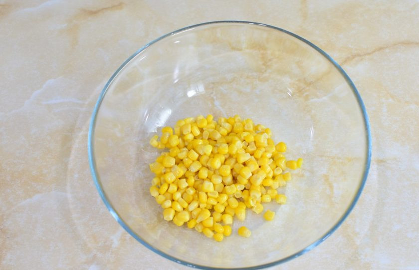 1. Этап. Салат с семгой и кукурузой: Откройте банку с консервированной кукурузой и слейте с неё жидкость. Выложите кукурузу в чашу.