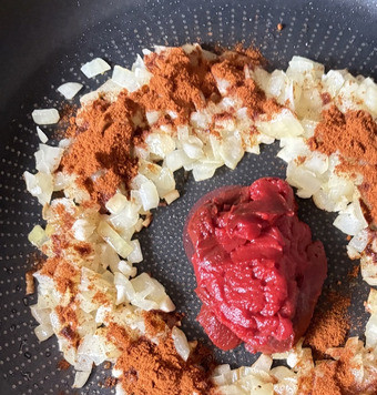 1. Этап. Турецкая паста с чечевицей: Мелко нарезанный лук и чеснок (2 дольки) обжарить на 1 ст. ложке оливкового масла. Добавить томатную пасту и 2 ч. ложки сладкой паприки, перемешать и потушить всё вместе пару минут.