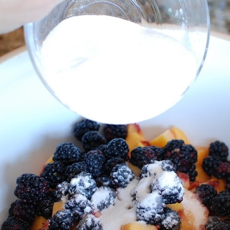 1. Этап. Десерт из персиков и ежевики: Засыпаем ягоды крахмалом и сахаром (1/3 стакана).