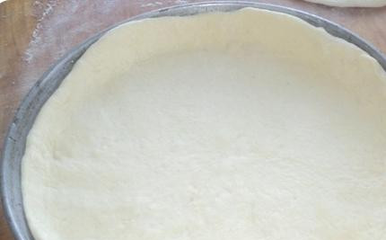 1. Этап. Пирог с урюком: Больший кусок теста раскатать в круглый пласт и уложить в смазанную маслом форму для выпекания.