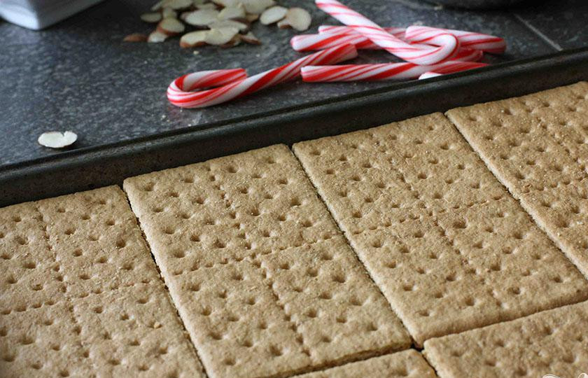 1. Этап. Шоколадные пирожные с миндалем: 1. Предварительно разогреть духовку до 175 градусов. Нарезать миндаль. Равномерно выложить на противне целые крекеры вплотную друг к другу. Крекеры должны заполнить почти все пространство. Используйте столько крекеров, сколько вам нужно, чтобы заполнить все пространство.