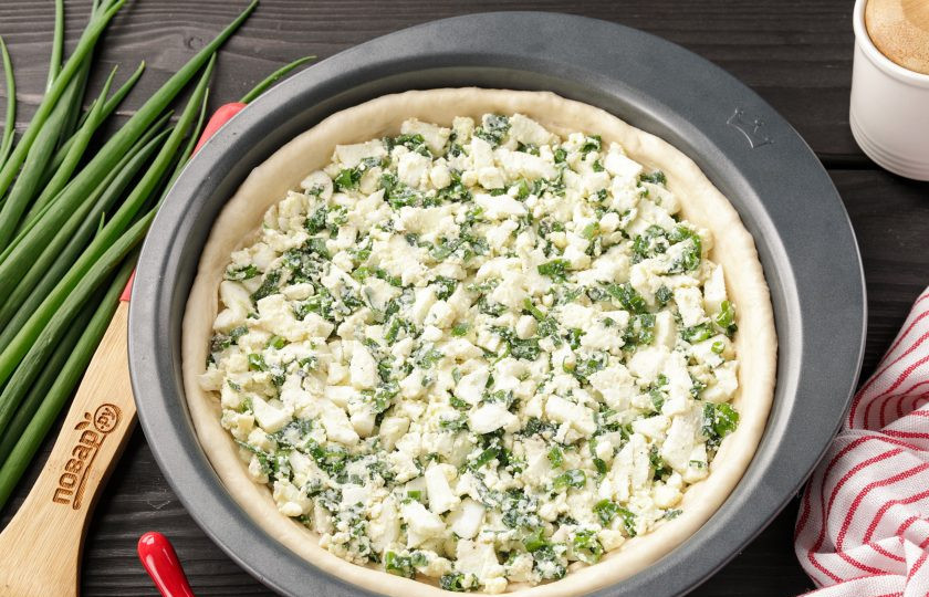 1. Этап. Дрожжевой пирог с яйцом в духовке: Выложите тесто в смазанную маслом форму и сформируйте руками высокие бортики. Сверху распределите начинку.