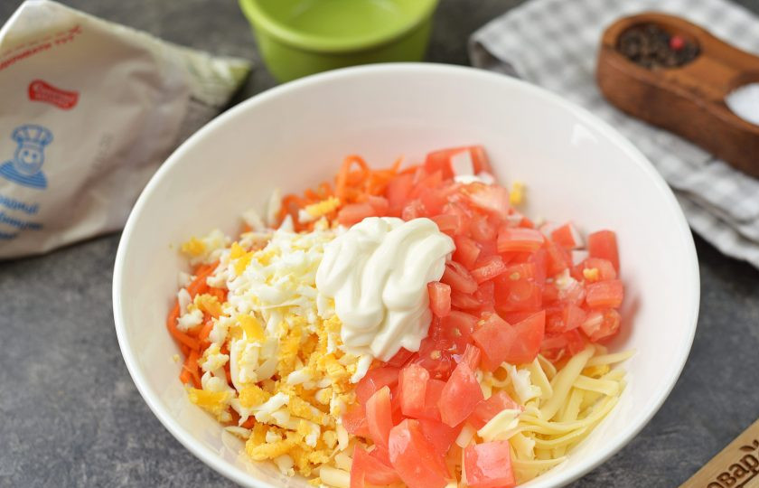 1. Этап. Салат из крабовых палочек, моркови по-корейски и сыра: Вырежьте место плодоножки на помидоре, удалите семечки, мякоть нарежьте кубиком. Заправьте салат любимым майонезом, поперчите и чуть посолите все ингредиенты.