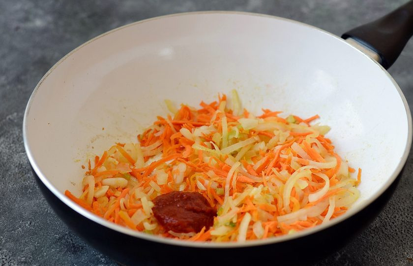 1. Этап. Суп с кольраби: Морковь и репчатый лук тонко нашинкуйте. Разогрейте в кастрюле масло, добавьте томатную пасту и обжарьте лук с морковью до мягкости. Добавьте измельченный чеснок.