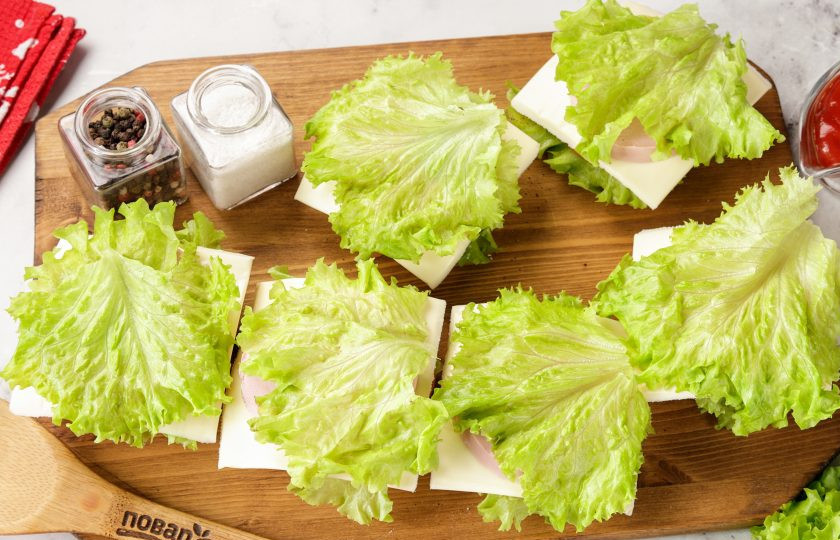 1. Этап. Праздничные бутерброды Змейка: Накройте начинку листиком салата.