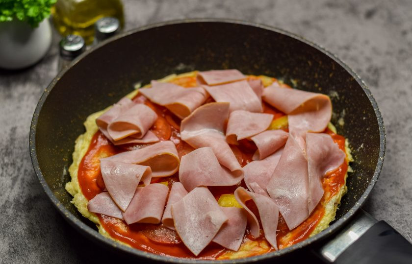 1. Этап. Быстрая пицца на сковороде из лаваша с яйцом: Выложите кусочки ветчины поверх овощей.