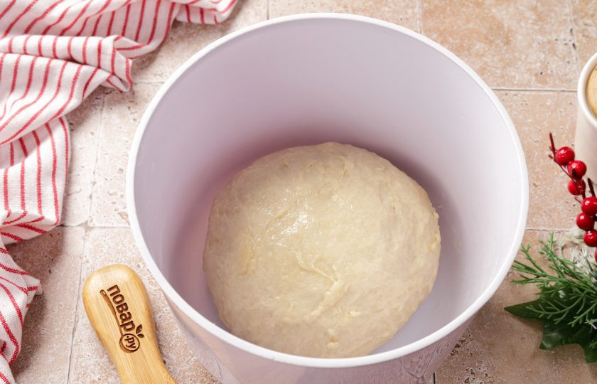 1. Этап. Новогодний пирог Змейка: Готовое тесто должно быть чуть липкое, но в то же время мягкое и пластичное. Соберите его в шар, смажьте растительным маслом, накройте миску пищевой плёнкой и оставьте в тёплом месте примерно на 1,5 часа.