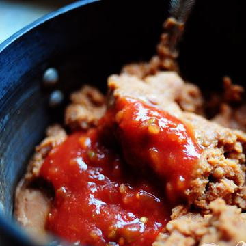 1. Этап. Мексиканская пицца: Выложите банку жареных бобов в кастрюлю. Добавьте некоторое количество сальса.