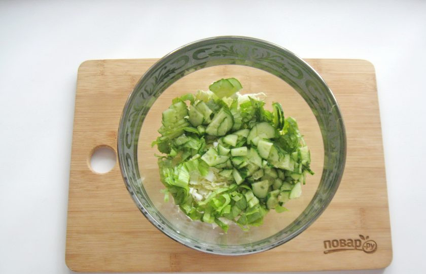 1. Этап. Постный салат из пекинской капусты: Огурец помойте и нарежьте тонкими пластиночками. Добавьте в салат.