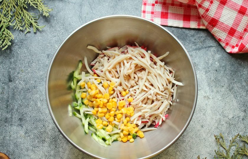 1. Этап. Салат с кальмарами, крабовыми палочками и кукурузой: С кукурузы слейте жидкость и выложите в салатник. Холодные кальмары порежьте тонкой соломкой и добавьте в салат.