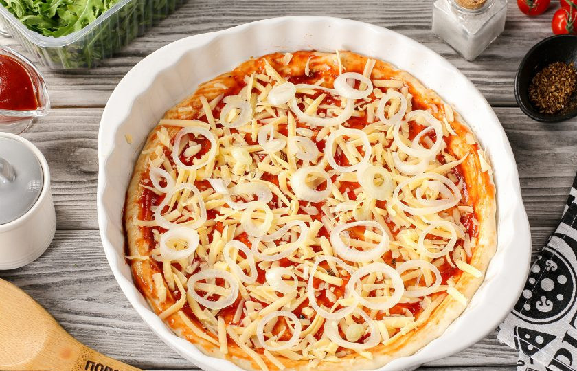 1. Этап. Пицца с рыбой: Сыр натрите на крупной тёрке. Подойдёт любой, который хорошо плавится. Часть сыра, примерно 2/3 посыпьте на соус, оставшийся оставьте для верха. Сверху разложите нарезанный колечками лук. Лук можно предварительно замариновать, я просто ошпариваю его кипятком, убирая горечь.