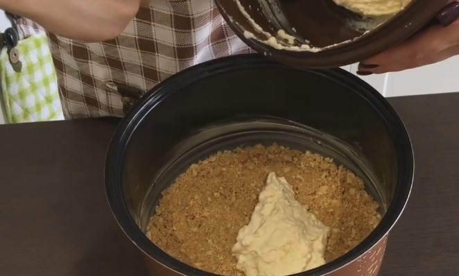 1. Этап. Творожный торт в мультиварке (и без неё): 8. Дно и бока чаши мультиварки смажьте маслом. Утрамбуйте пальцами крошку из печенья, делая небольшие бортики. Затем выложите половину теста и разровняйте.