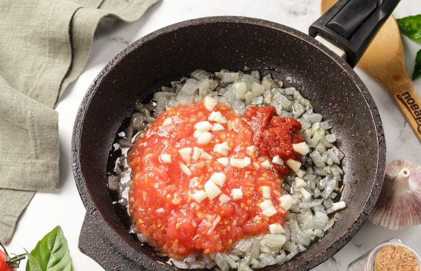 1. Этап. Треска, запеченная под соусом: Добавьте протёртые томаты, томатную пасту и нарезанный кубиками чеснок.