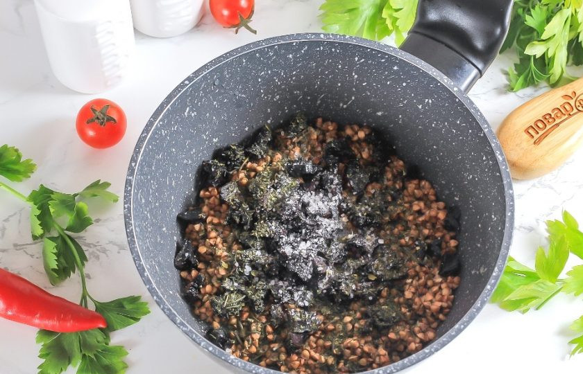 1. Этап. Постная гречневая каша с черносливом: Нарежьте чернослив мелкими кубиками и всыпьте с крупой в казан, кастрюлю или в ковш с антипригарным дном. Добавьте соль и сушеную зелень.