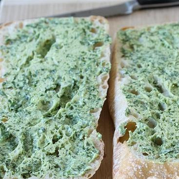 1. Этап. Бутерброды с базиликовым маслом: 2. Разрезать хлеб пополам и смазать две половинки приготовленным базиликовым маслом.