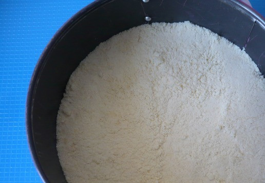 1. Этап. Пирог с творожным сыром и клубникой: Теперь берем разъёмную форму для выпечки диаметром 18 см. Дно формы закрываем пергаментной бумагой, бока формы ничем закрывать и смазывать не надо. Приступаем к заполнению формы насыпным тестом, кремом и ягодной начинкой. Должно получится 5 слоёв из крошки, поэтому делим визуально крошку на 5 частей. Посыпаем дно формы 1/5 частью крошки, равномерно разравниваем.