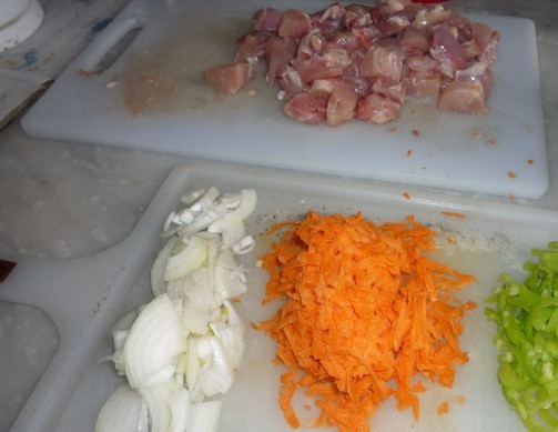 1. Этап. Гуляш из курицы с подливкой: Сразу подготовим все ингредиенты, чтобы не отвлекаться в процессе готовки. Обрезаем мясо с куриных бедрышек, нарезаем его на небольшие кусочки. Чистим лук и морковь. У перца удаляем сердцевину. Лук нарезаем полукольцами, перец - соломкой, морковь натираем на терке.