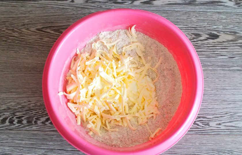 1. Этап. Печенье с кунжутом Чиполлино: К сыпучим продуктам добавьте сметану. Натрите на терке холодное масло. Содержимое чаши перетрите слегка руками.