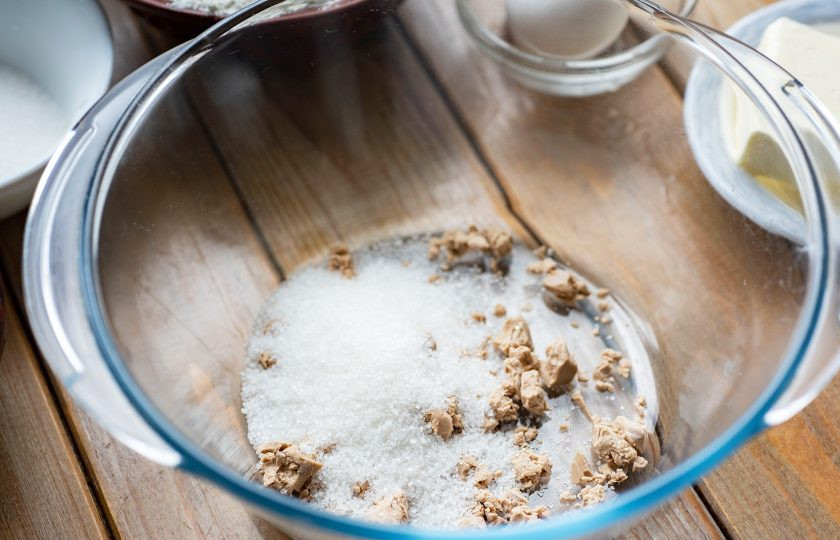 1. Этап. Булочки с овсяными хлопьями: В просторную миску разотрите пальцами свежие дрожжи, добавьте столовую ложку сахара.