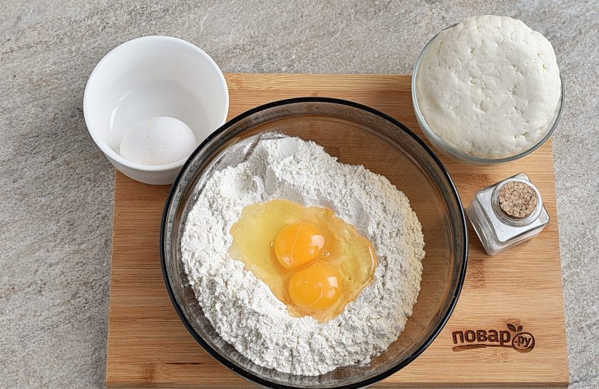 1. Этап. Вареники с адыгейским сыром: В миску всыпьте муку и соль. Перемешайте и соберите муку горкой. Сделайте углубление и вбейте два яйца. Понемногу вливая холодную воду, замесите крутое тесто.