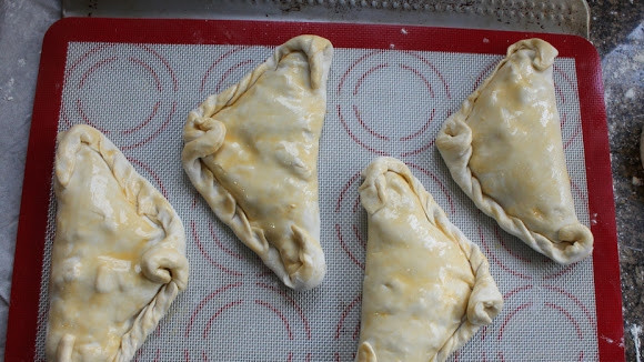 1. Этап. Пирожки с сюрпризом: 9. Выложите пирожки на противень, застеленный пергаментом или силиконовым ковриком. Смажьте верх оставшимся яйцом, отправьте в разогретую до 180 градусов духовку.