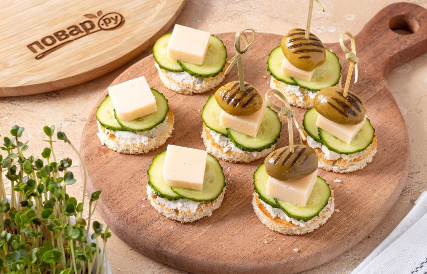 1. Этап. Канапе с огурцом и сыром: Добавьте сыр, а сверху оливку. Закрепите канапе шпажкой.