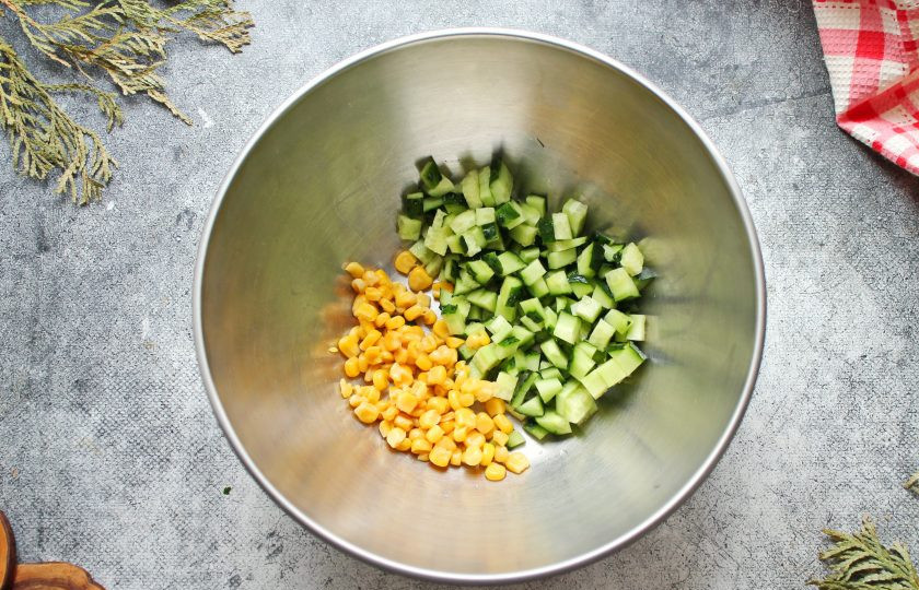 1. Этап. Салат с треской и кукурузой: У огурца отрежьте хвостики и порежьте мелким кубиком. Огурец и кукурузу выложите в салатник.