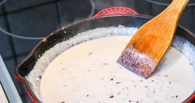 1. Этап. Куриная грудка под сырным соусом: Влейте в сковороду сливки. Уменьшите огонь. Готовьте соус до загустения.