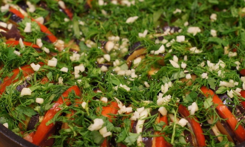 1. Этап. Запеканка из кабачков и баклажанов: Сверху выкладываем измельченный чеснок и свежую зелень, сбрызгиваем запеканку растительным маслом.