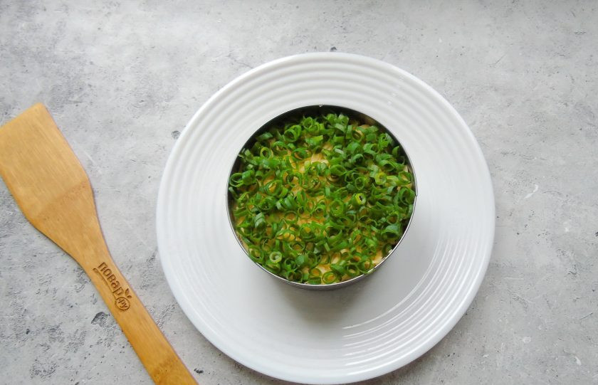 1. Этап. Слоеный салат Лесная поляна с маринованными опятами: Зеленый лук мелко нарежьте и покройте им слой сыра.