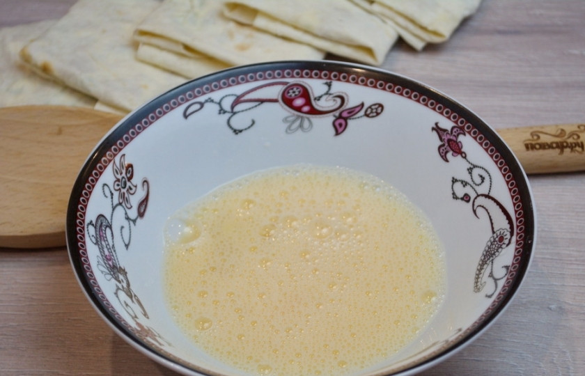 1. Этап. Лаваш в кляре: Приготовьте кляр. Для этого смешайте яйцо с 2-3 ст. ложками молока. Добавьте немного соли, взбейте.