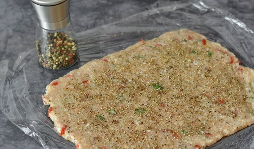 1. Этап. Рулет из индейки с ягодами годжи: На рабочей поверхности расстелите плёнку. Выложите фарш слоем примерно 1 см, разровняйте его лопаткой или ложкой. И щедро по всей поверхности посыпьте чёрным молотым перцем из мельницы. Слой должен быть заметен. Вместо чёрного перца можете взять сладкую паприку или другие не острые специи. Особенно, если будете готовить для детей, с перцем будьте осторожны.