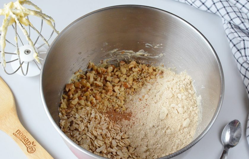 1. Этап. Овсяное печенье с яблоками без муки: Порубите мелко грецкие орехи. Выложите в чашу миксера овсяные хлопья, овсяную муку, корицу, разрыхлитель и орехи.