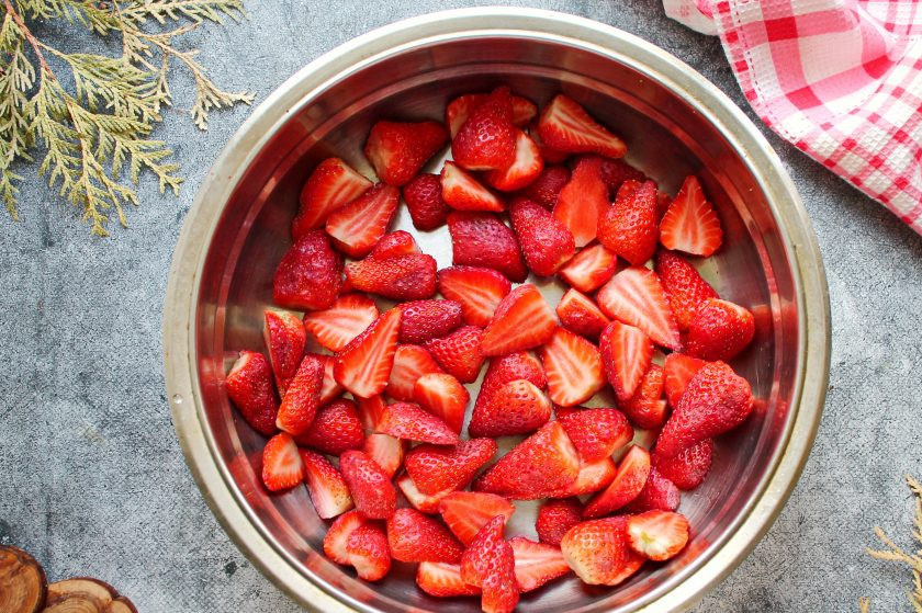 1. Этап. Варенье из клубники с розовым перцем: У клубники удалите хвостики. Разрежьте клубнику пополам. Выложите клубнику в емкость для варки.