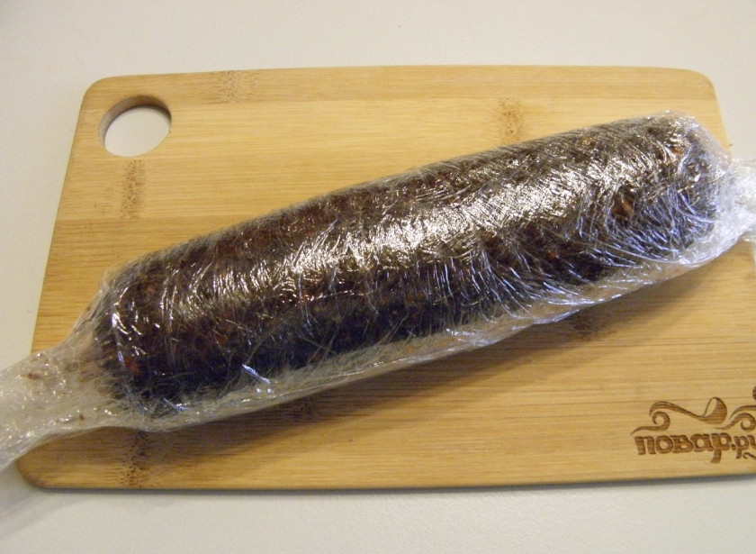 1. Этап. Сладкая колбаска: На столе разложите в несколько слоев пищевую пленку, выложите на неё половину сладкой массы, аккуратно, прижимая заверните. Края скрутите, как у конфетки, это позволит уплотнить колбаску. Уберите ее на 3-4 часа в холодильник, чтобы масло застыло и колбаска приняла форму.