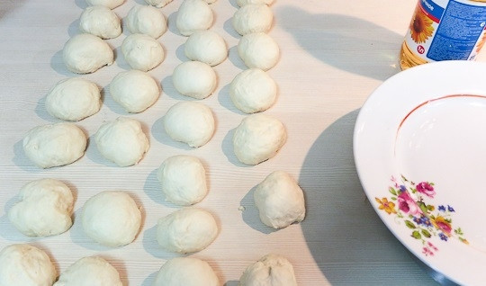 1. Этап. Беляши Советские: 7. Разделите тесто на маленькие кусочки, сформируйте из них шарики, выложите на столешницу, смазанную растительным маслом.